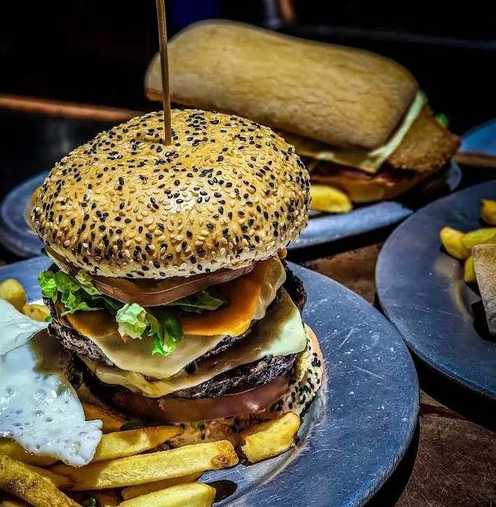 Hamburguesa de autor con papas en plato de piedra